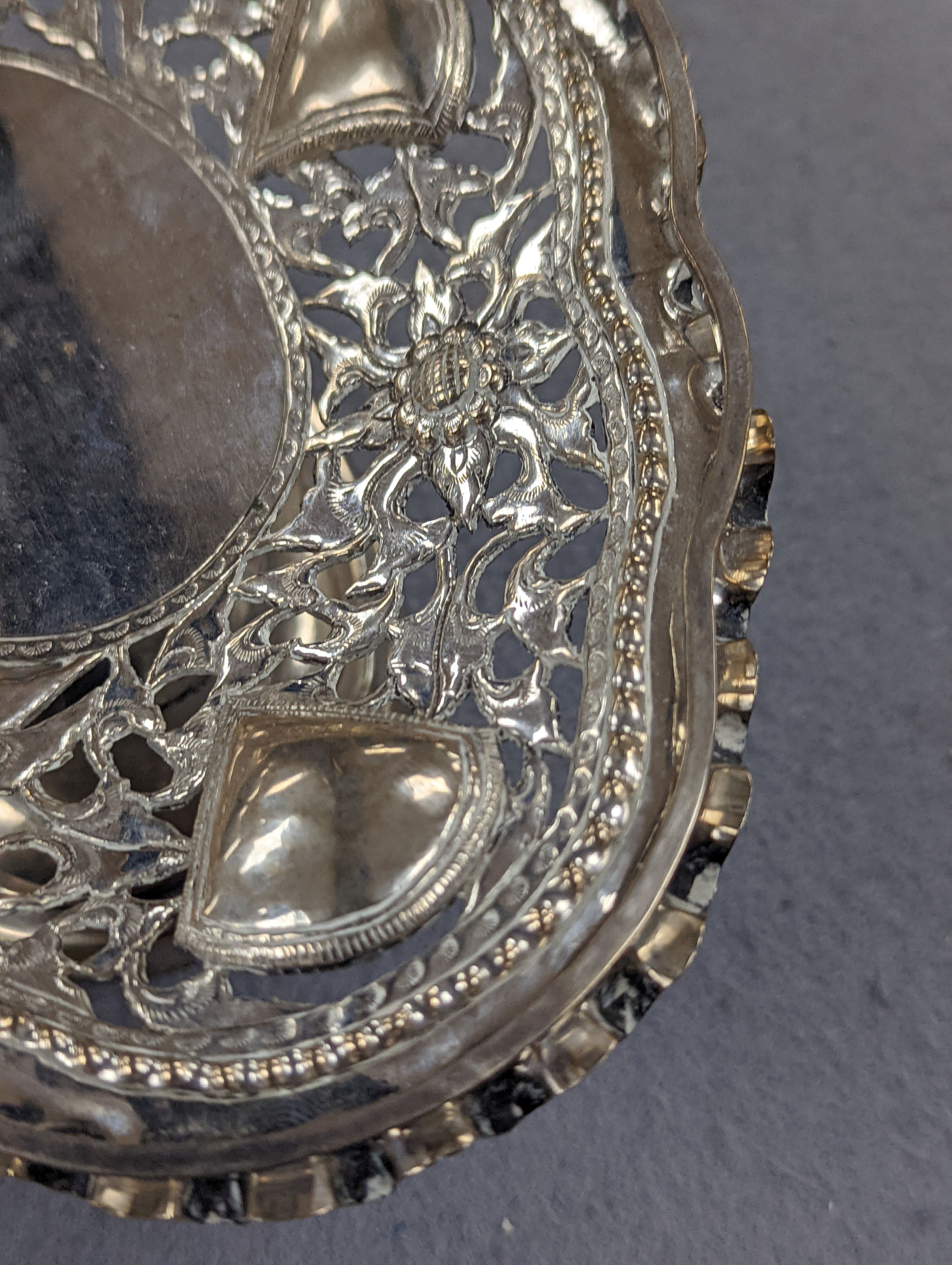 A Chinese pierced and embossed white metal shaped oval pedestal basket, length 21.6cm, 9oz, signed on base.